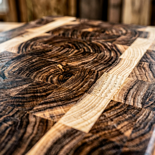 End-grain walnut cutting board with vegetables and chef knife on kitchen counter